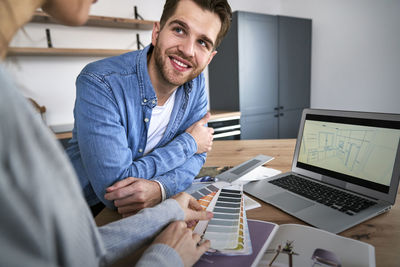 Portrait of young man using laptop at office