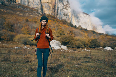 Full length of smiling young woman standing on land