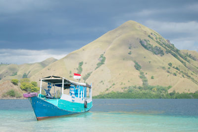 Person in boat on sea against mountain