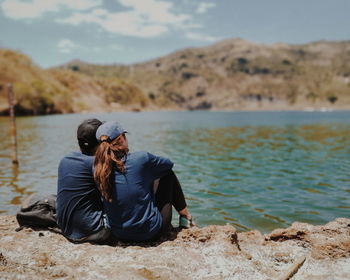 Rear view of women sitting on shore at beach