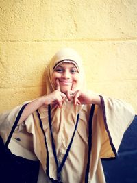 Portrait of smiling young woman standing against wall