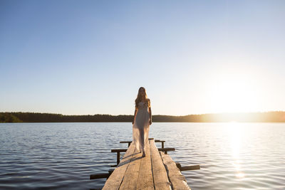 Young woman wearing dress walking on jetty