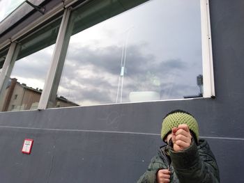 Close-up of boy hiding face against building