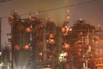 Illuminated factory against sky at night