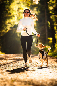 Woman wearing sunglasses walking dog on road