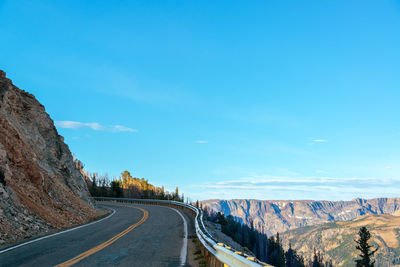 Road amidst trees against blue sky