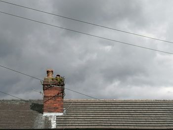 Low angle view of power lines against cloudy sky