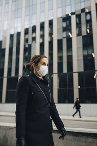 Female entrepreneur walking by building during covid-19