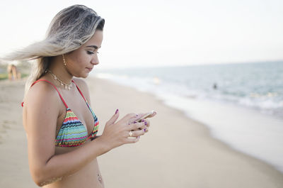 Young woman using smart phone at beach