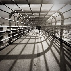 Rear view of woman walking in bridge on sunny day