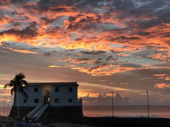 Houses by sea against sky during sunset