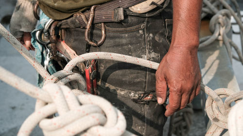 Midsection of worker with tied rope