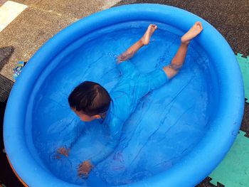 High angle view of boy swimming in wading pool