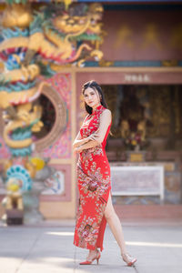 Full length portrait of woman standing against multi colored umbrella