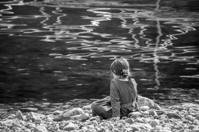 Full length of girl sitting by the water