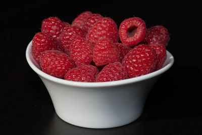 Close-up of strawberries in bowl against black background