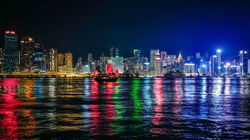 Illuminated skyscrapers at night by sea