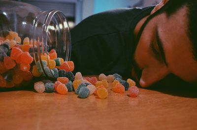 Man sleeping at table by sugar candies and jar