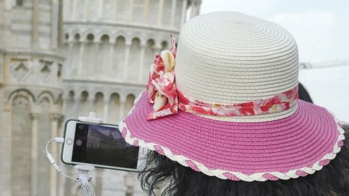 Rear view of woman wearing pink hat against defocused pisa tower taking photo 