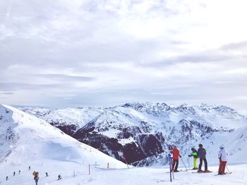 People skiing on snowcapped mountain against sky