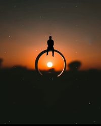 Silhouette person standing by illuminated light against sky at night