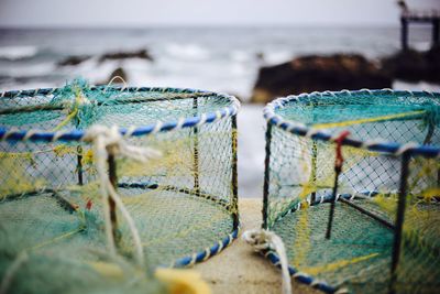 Close-up of fishing net at beach against sky