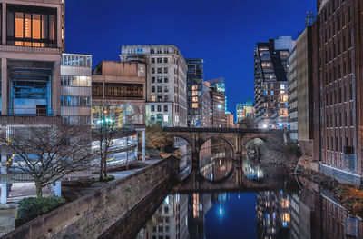 Victoria bridge over canal in city against clear sky at dusk in manchester, england.