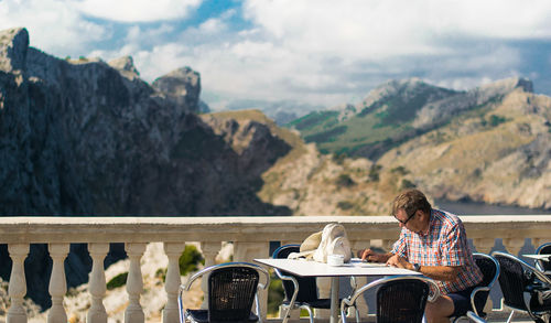 Man sitting on railing against mountains