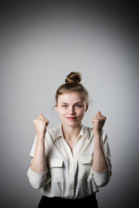 Portrait of young woman standing against white background