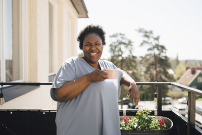 Happy woman having coffee in balcony