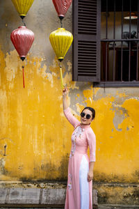 Portrait of woman holding lantern outside house
