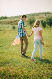 Full length of happy woman walking on grassy field