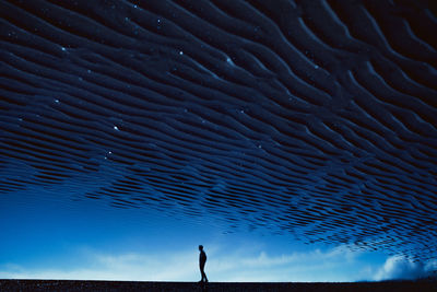 Silhouette person standing in sea against sky at night