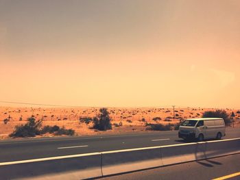 Cars on road against sky during sunset