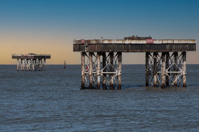 Pier over sea against clear blue sky