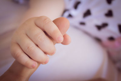 Cropped image of parent and baby holding hands