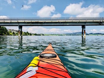 Kayak on river under bridge against sky