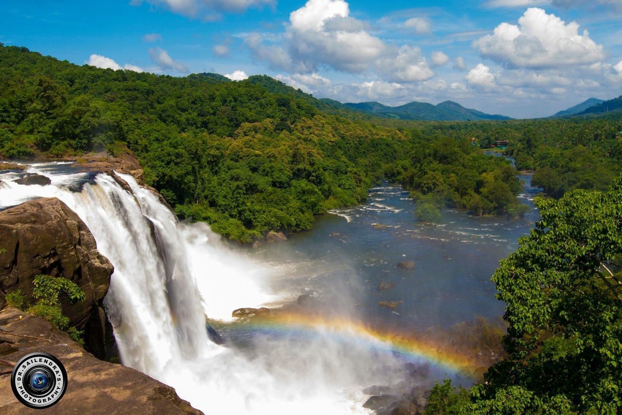 SCENIC VIEW OF WATERFALL AND TREES AGAINST SKY