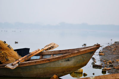 Old rowboat moored at riverbank during foggy weather