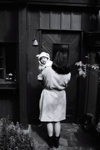 Rear view of woman standing against door