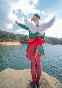 Full length of woman standing by lake against sky