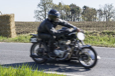 Rear view of man riding motorcycle on road