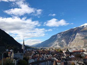 Aerial view of townscape by mountains against sky