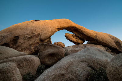 Low angle view of rocks against clear blue sky