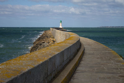 Lighthouse by ocean against sky