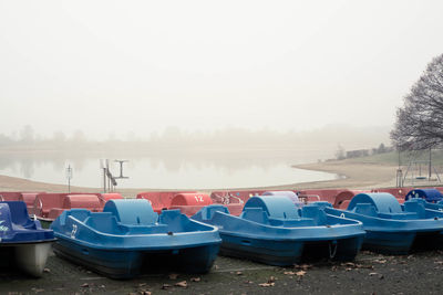 Boats moored on beach against sky during winter