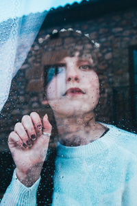 Close-up portrait of woman seen through glass window