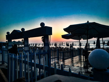 Silhouette people by sea against clear sky at sunset