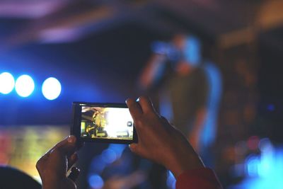 Midsection of man using smart phone at music concert