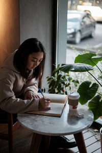 Side view of young woman using mobile phone at home